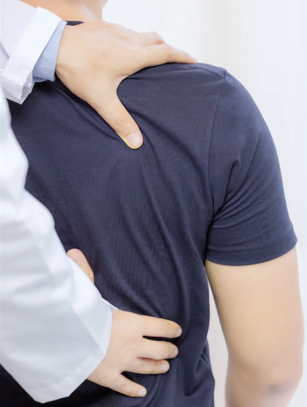 A chiropractor examining a patient's shoulder and back